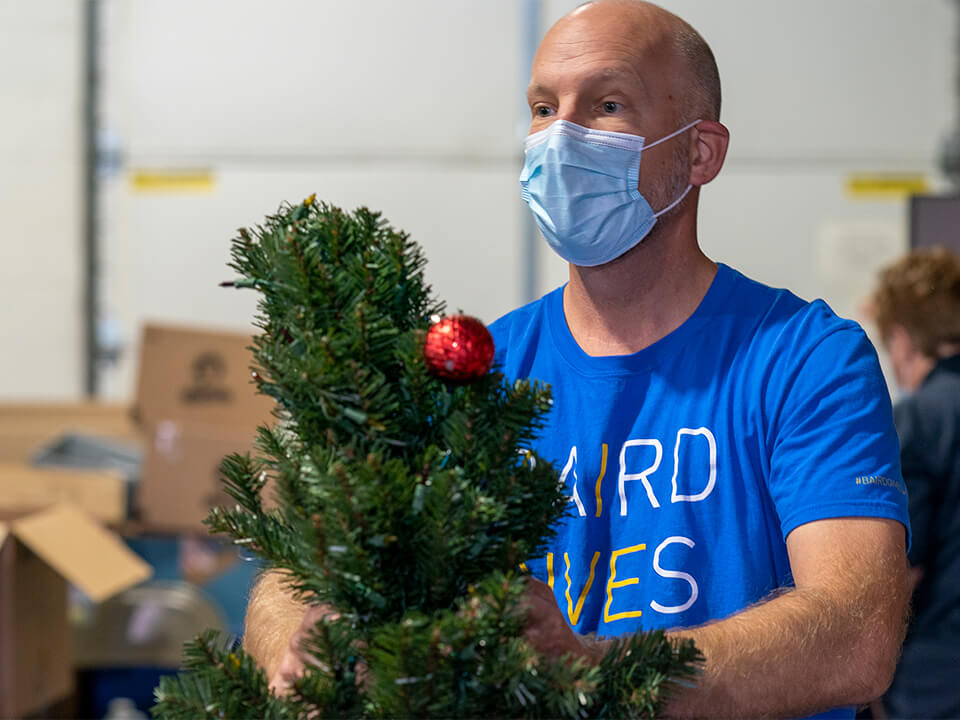A Baird Trust associate carries a Christmas Tree at Home of the Innocents