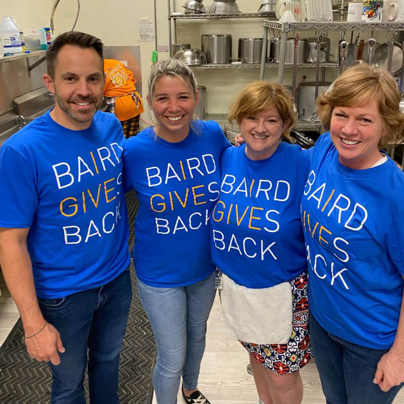 A group of volunteers wearing Baird Gives Back t-shirts at Community Kitchen
