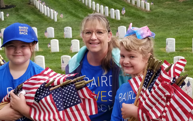 A woman and two children carry armfuls of flags