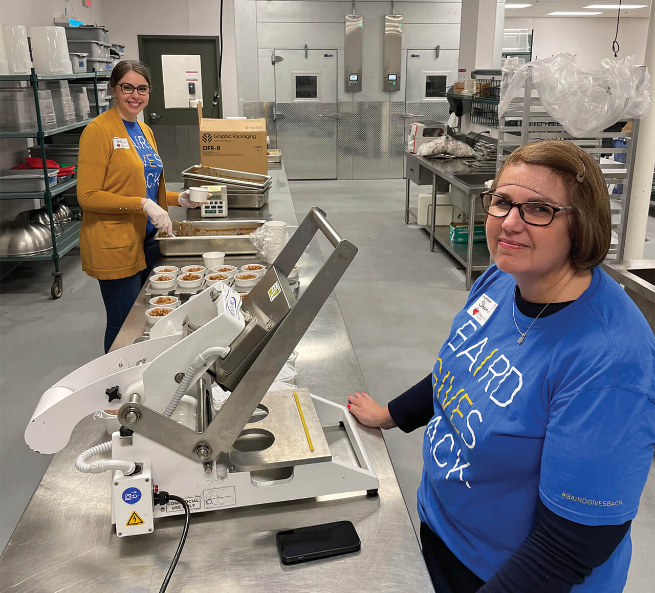 Two associates volunteering in the kitchen of Dare to Care