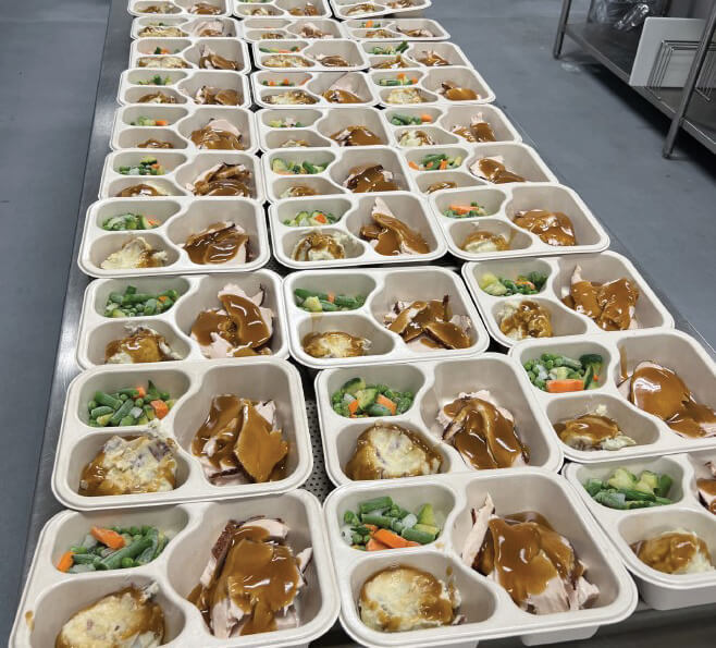 A table filled with pre-plated turkey dinners in the kitchen of Dare to Care