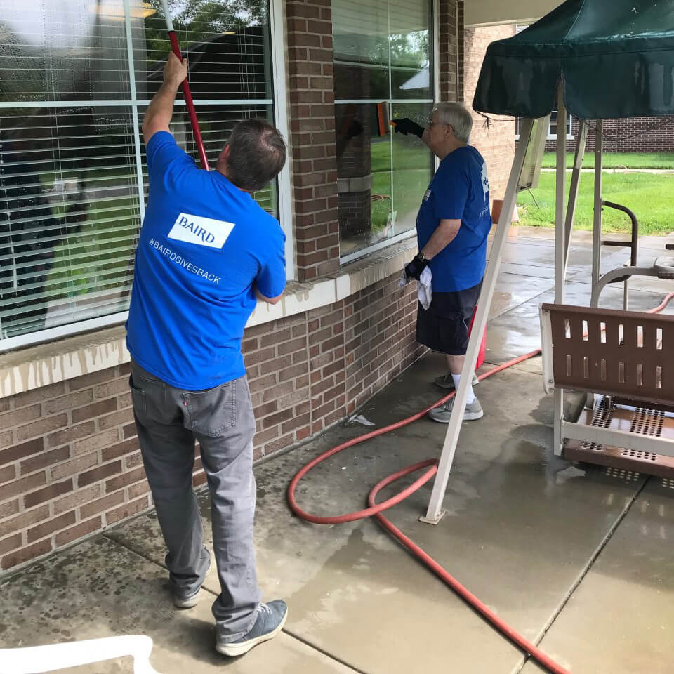 Two associates in Baird Gives Back t-shirts wash windows at Home of the Innocents
