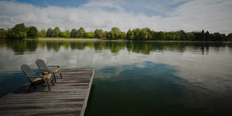 Two chairs on a pier extending out into a lake