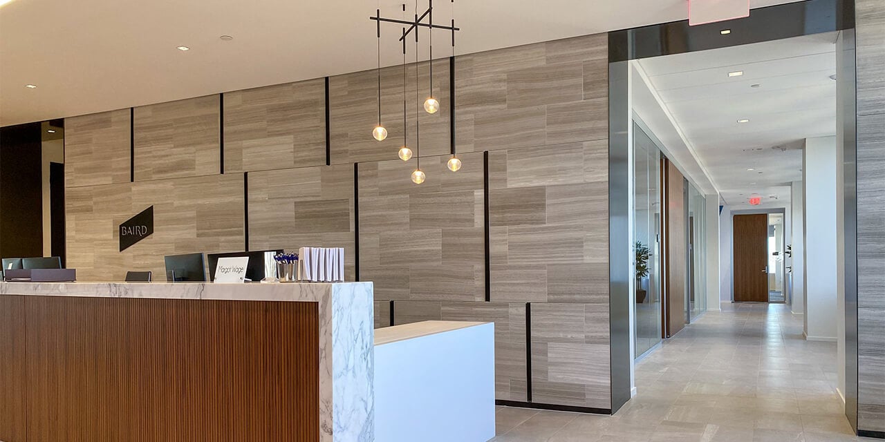 Angled photo of a long reception desk infront of a sleek, gray, textured wall in the new Louisville Conference Center