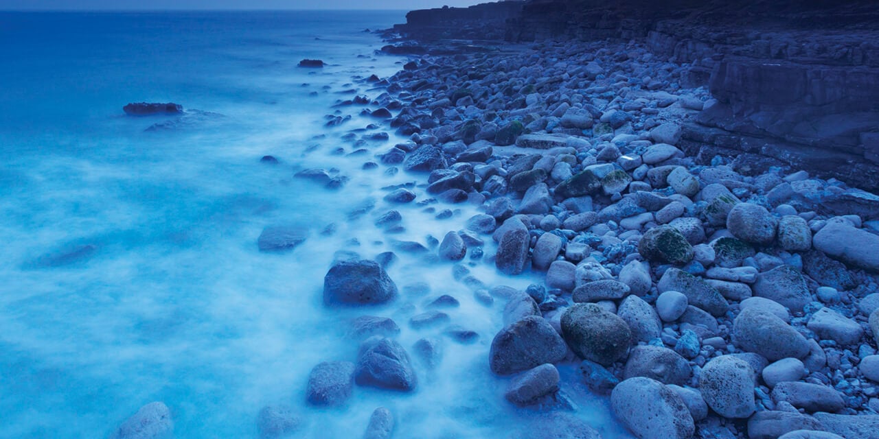 Landscape image of a rocky shoreline at dusk